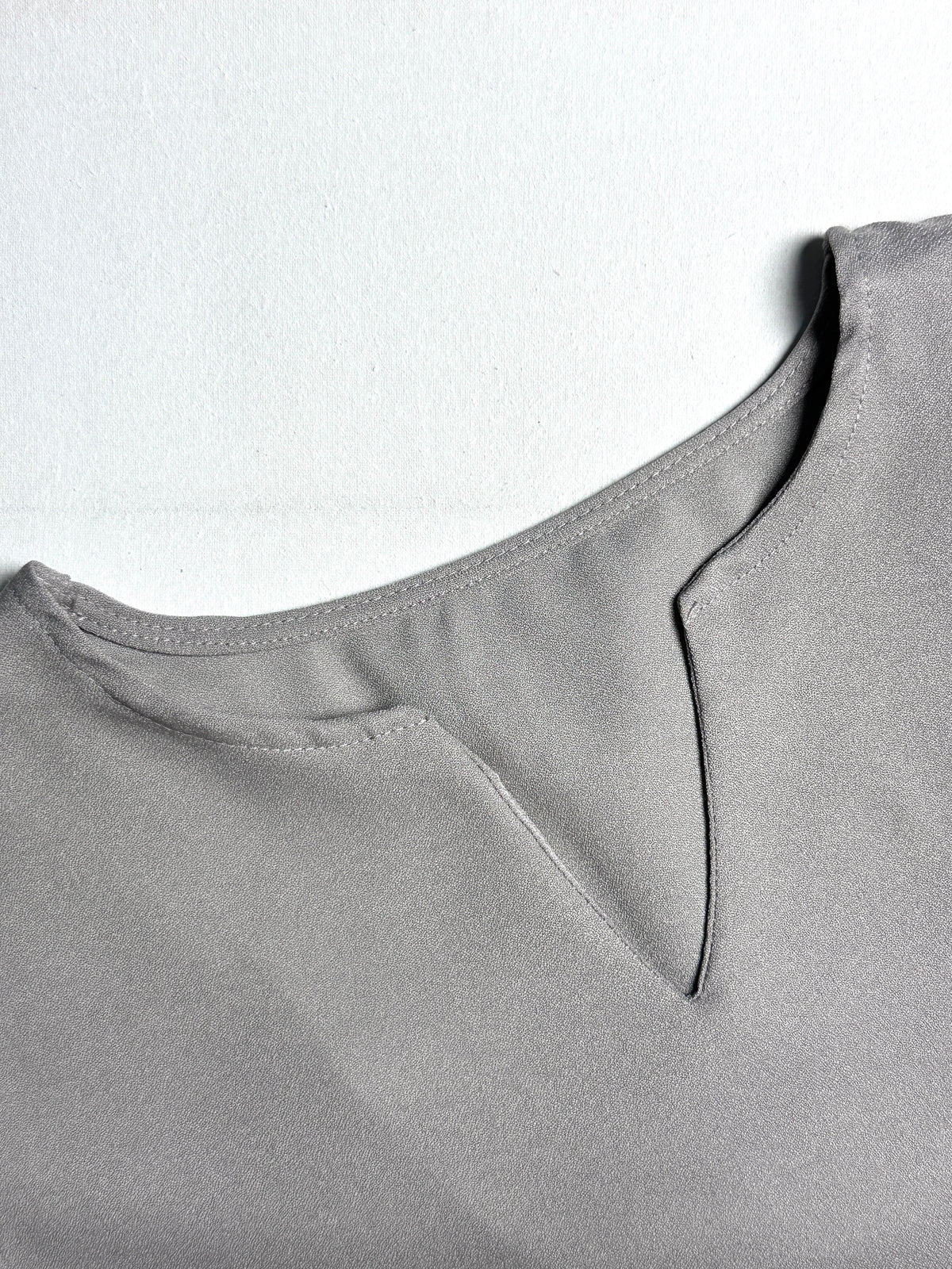 Minimalist Taupe Split-Neck Blouse with Curved Hem & Long Sleeves